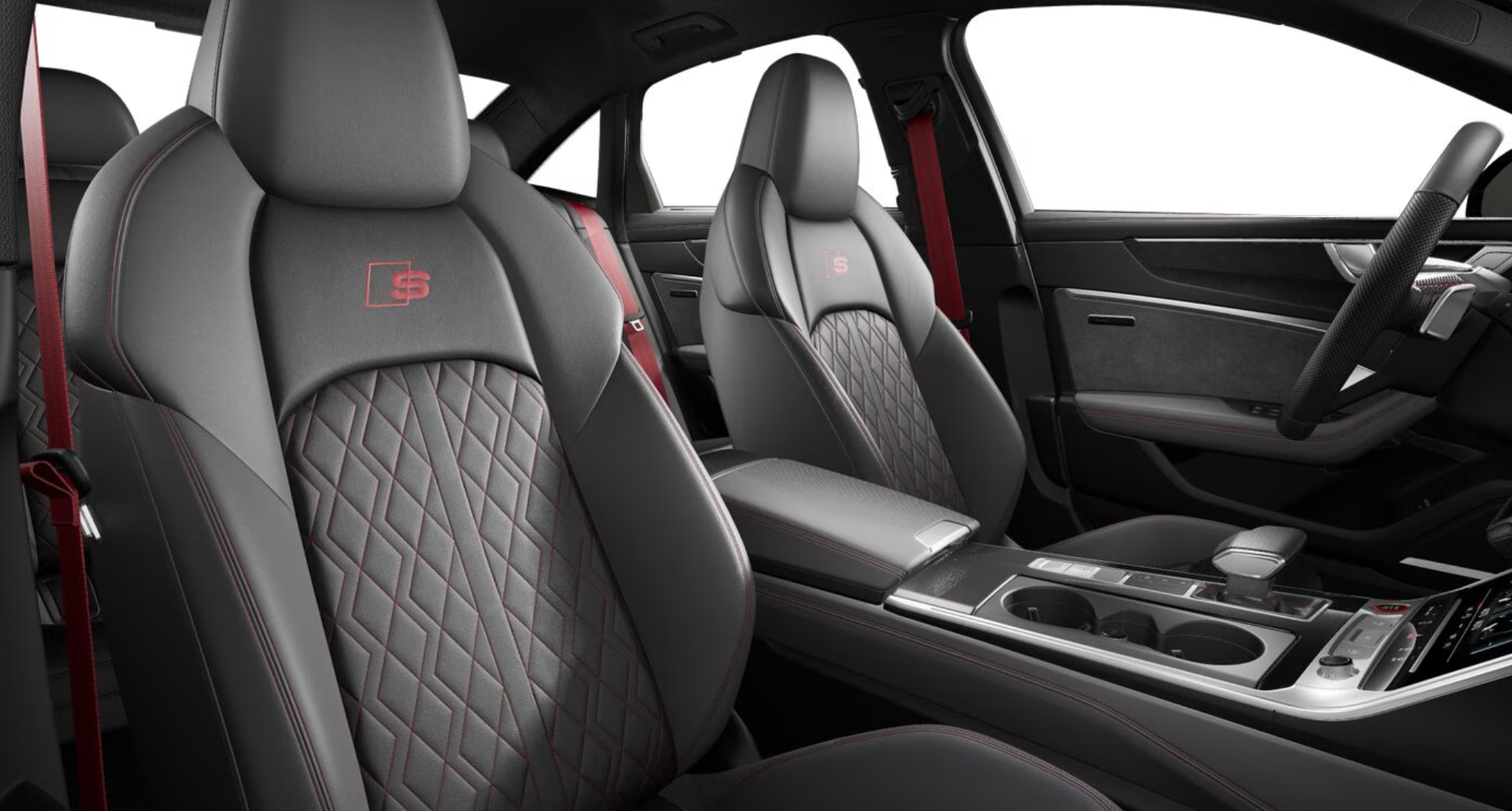 Luxurious front seats of the 2025 Audi S6, upholstered in diamond-stitched leather with red accents and the signature "S" badging, complemented by sporty red seat belts.