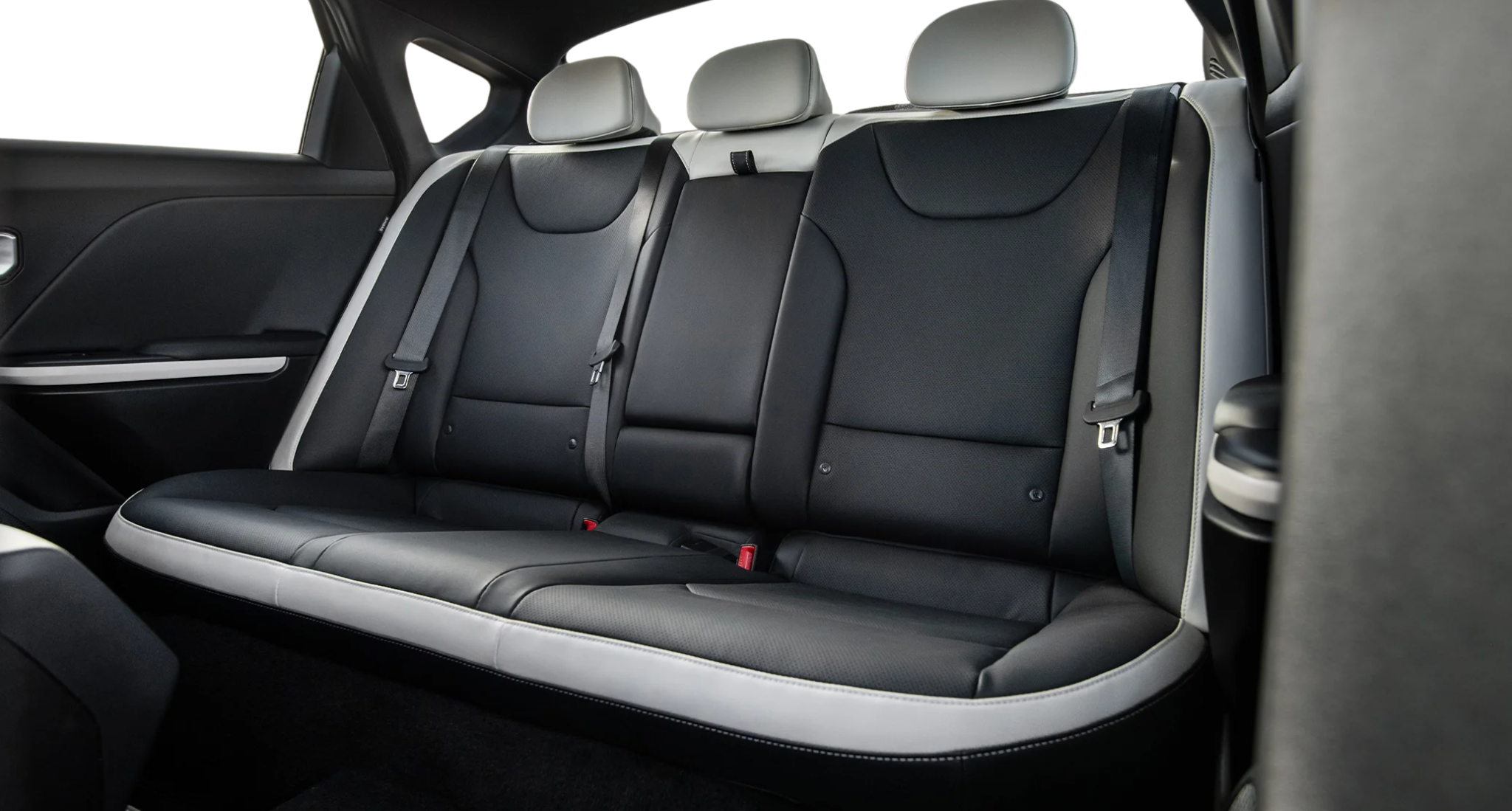 Rear seat view of the 2025 Kia K4 LX, featuring spacious black leather-trimmed seats with white accents, ergonomic headrests, and premium stitching for enhanced passenger comfort.