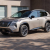 Angle view of the 2025 Nissan Rogue parked in front of a garage, showcasing its sleek crossover SUV design and bold V-Motion grille for car leasing enthusiasts.